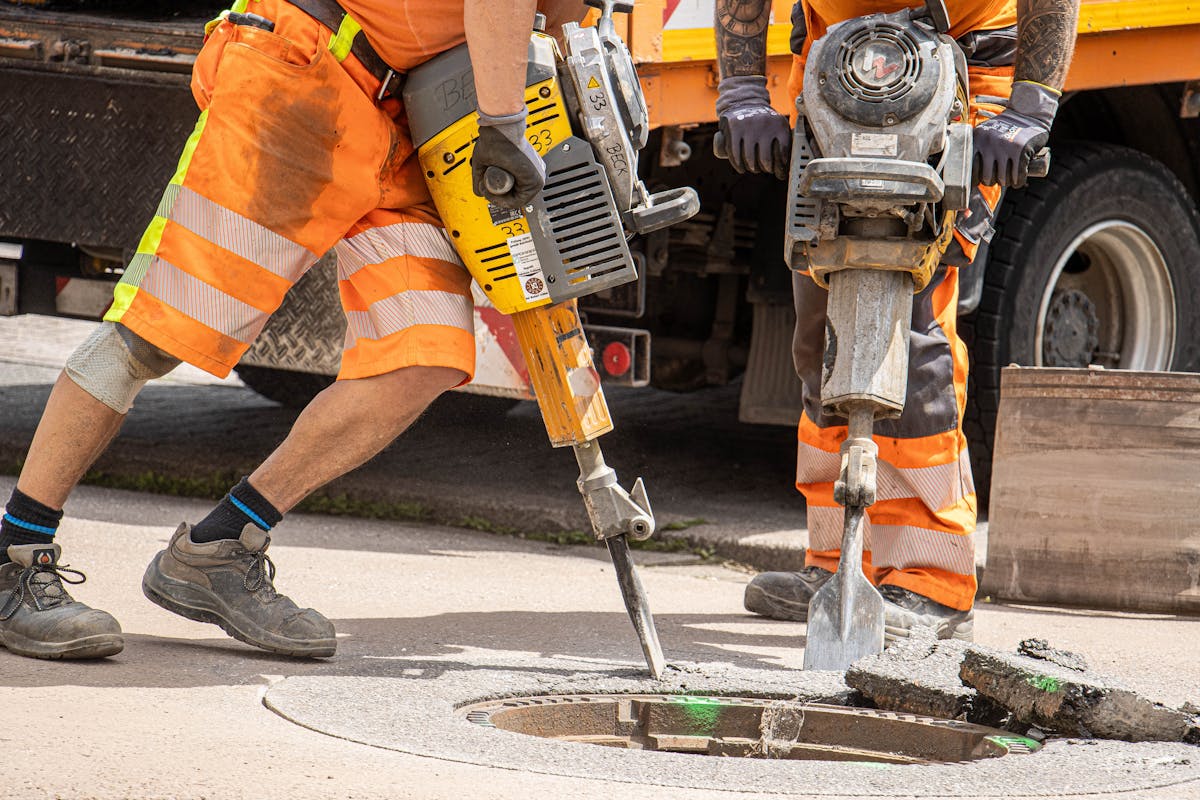 Road construction workers using jackhammers on asphalt