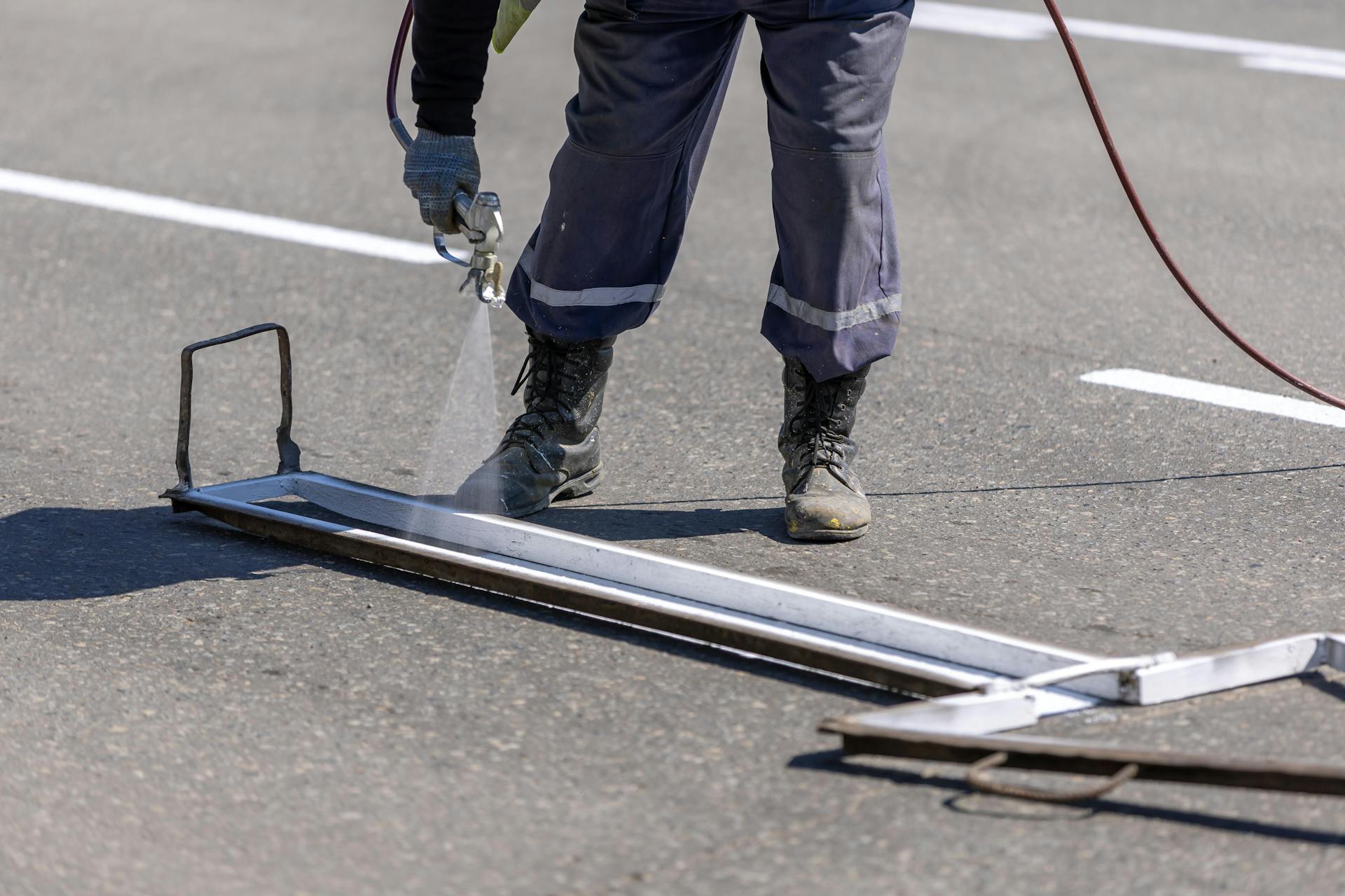 Worker painting road lines during daytime